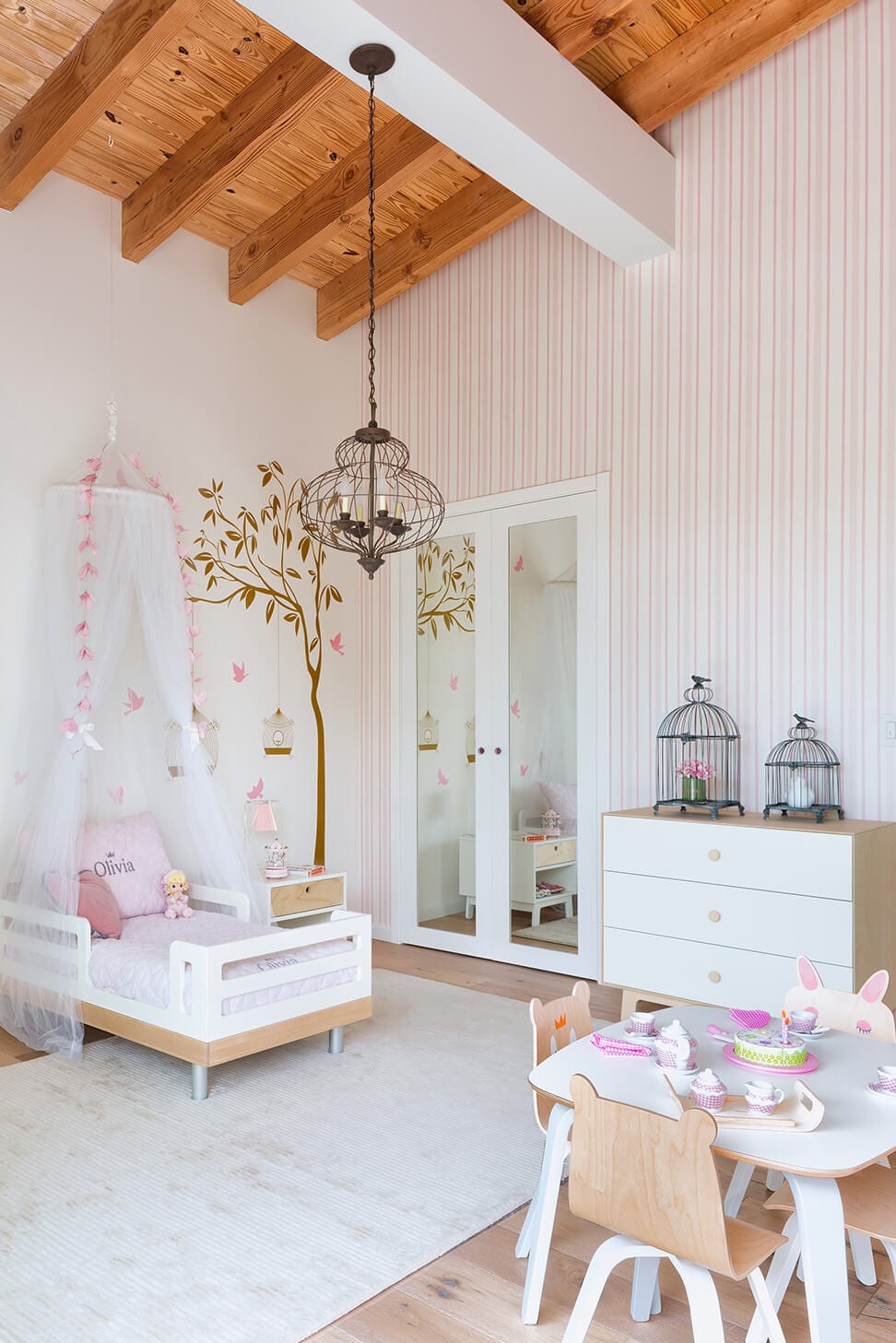 A white bed canopy with pink ornament in a sweet girl's room